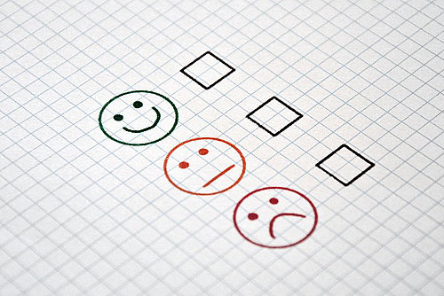 athree23/pixabay.com/CC0 Bild eines karierten Blattes auf dem 3 Smilies, ein zufriedener, ein gleichgültiger und ein unzufriedener Smiley zu sehen sind.