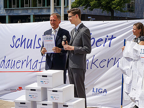 Foto: Daniel Dinse Männer, die Unterschriftslisten präsentieren, Frau steht am Rand mit Transparent