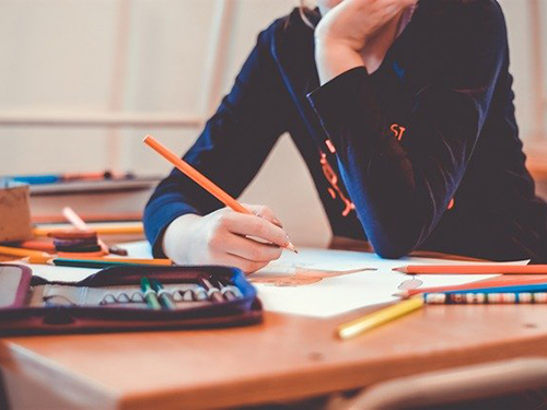 Bild: coyot/pixabay.com/CC0 Foto einer Person, die am Schreibtisch sitzt und mit Buntstiften etwas auf Papier malt