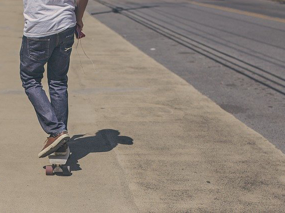 Rückansicht einer Personen, die auf einem Skateboard fährt.